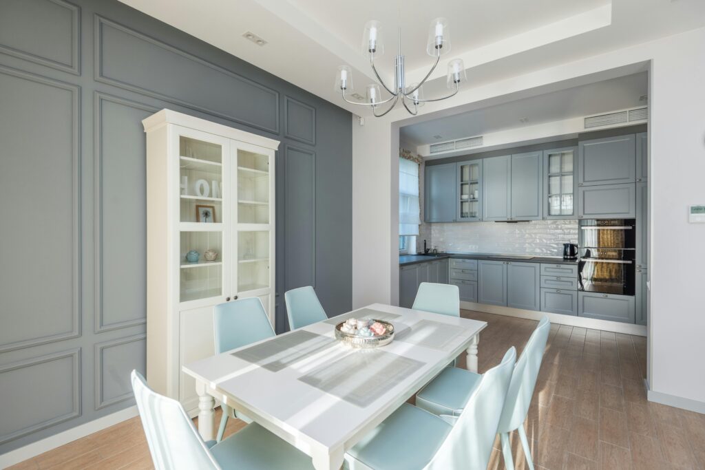 Contemporary kitchen with gray cabinets and elegant dining area in soft pastel tones.